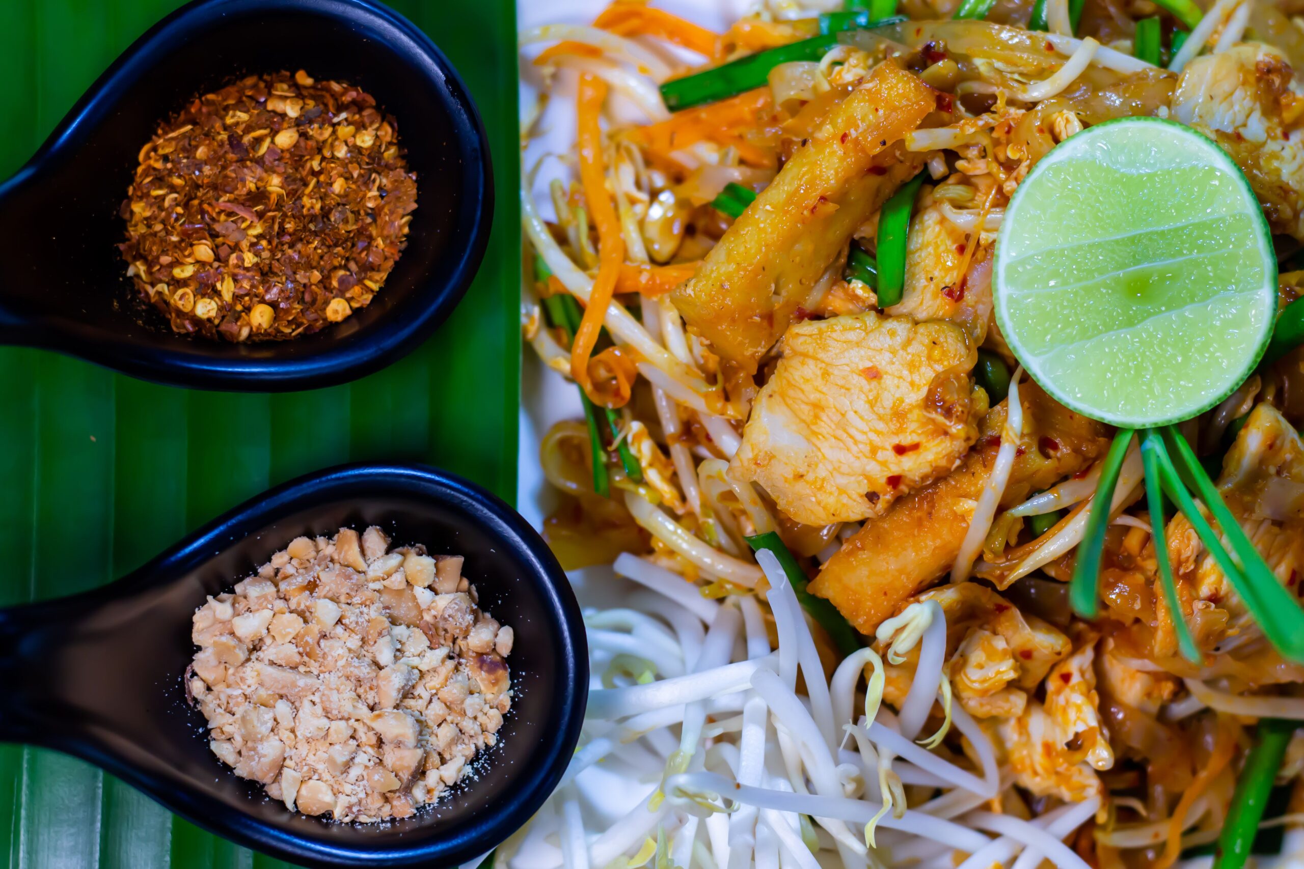Pad Thai served with lime, peanuts, and chili flakes, embodying authentic Thai
