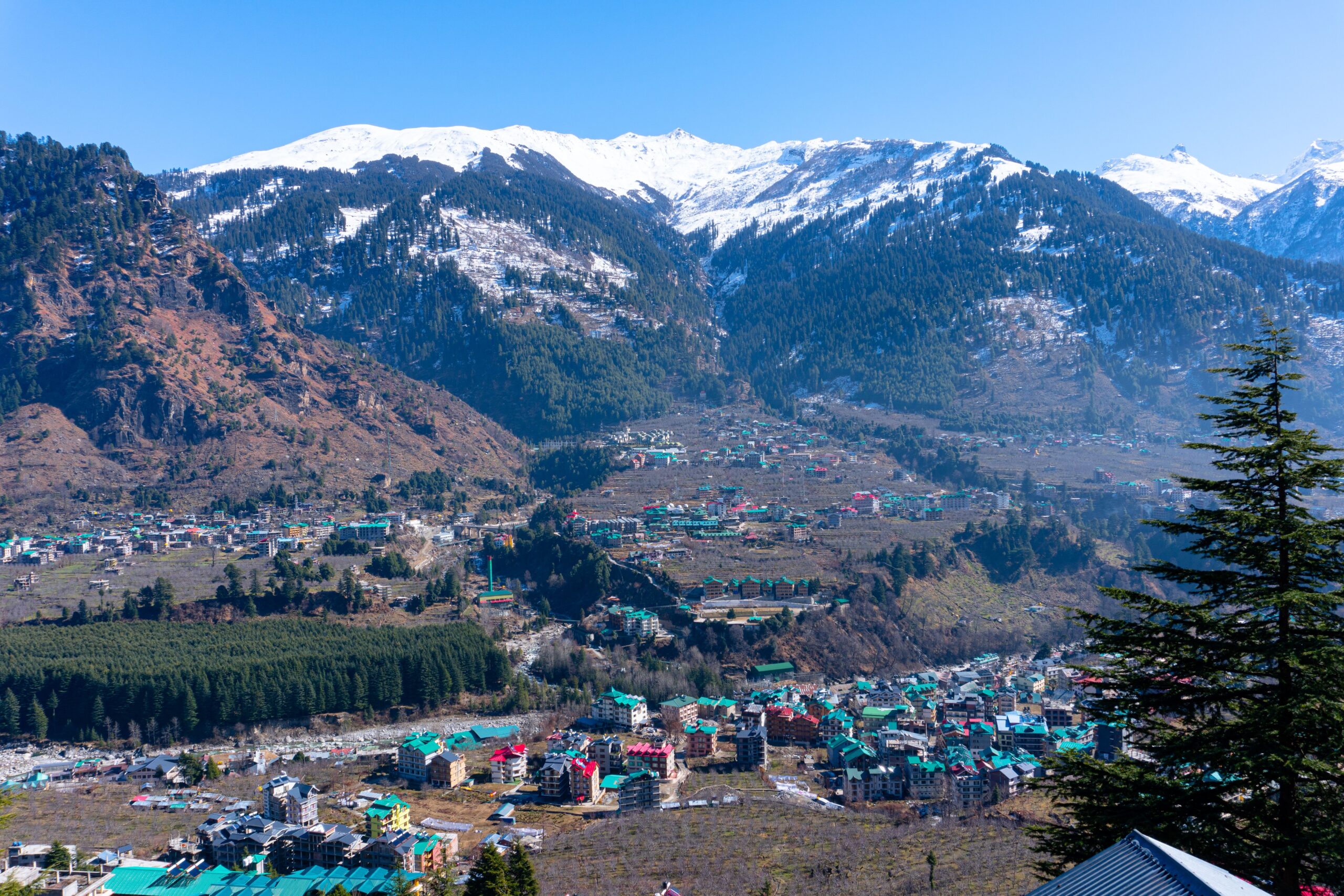 Manali nestled in the Himalayan mountains under a clear blue sky scaled
